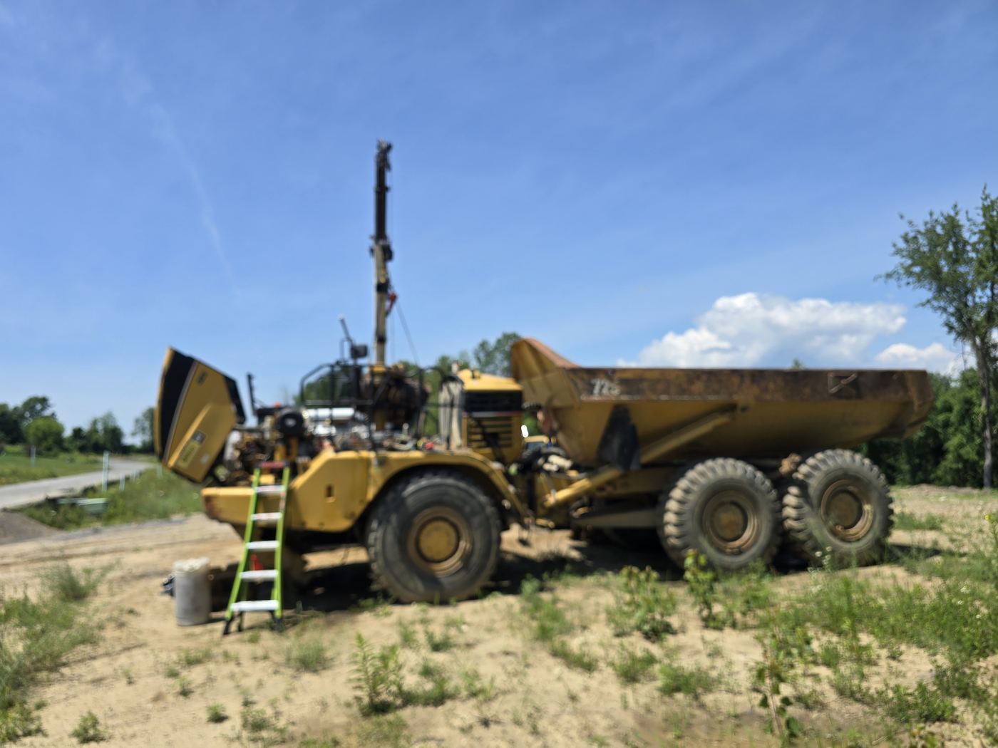 Articulated dump truck with the engine hood open during an on-site repair at a job site